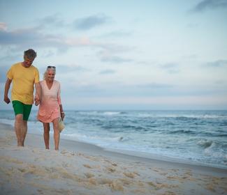 Snowbird couple walking along the shore in Orange Beach