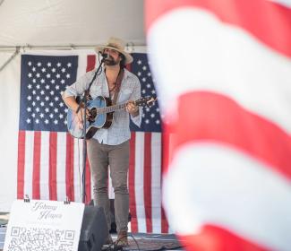 Musician performing in front American flags at Freedom Fest