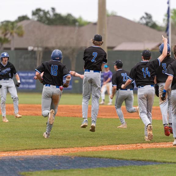 Baseball team celebrating a win on the field at the Gulf Coast Classic in Gulf Shores