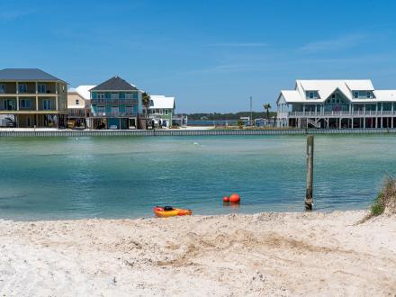 Scenic view of Lagoon Pass in Gulf Shores with colorful waterfront buildings, ideal for a beach vacation stay.
