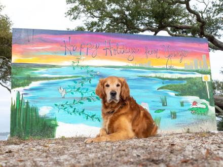 Dog sitting in front of a giant Christmas Card in Gulf State Park