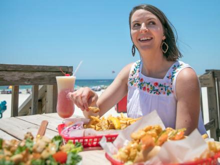 Woman dining on the deck at Pink Pony Pub in Gulf Shores