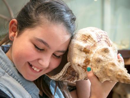 Girl holding a seashell to her ear