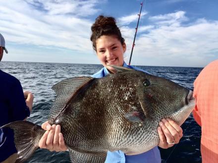 Woman holding a large distraction triggerfish caught in the Gulf