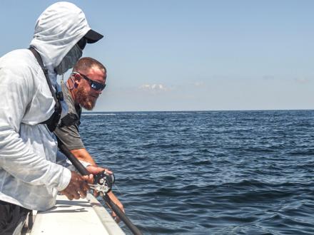Two men fishing offshore on a charter boat