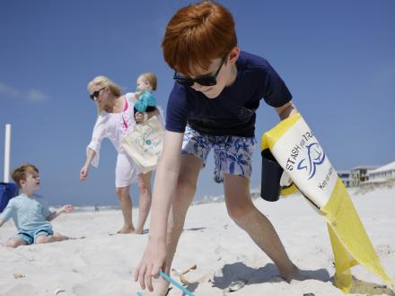 Kid picking up trash along Alabama's Beaches
