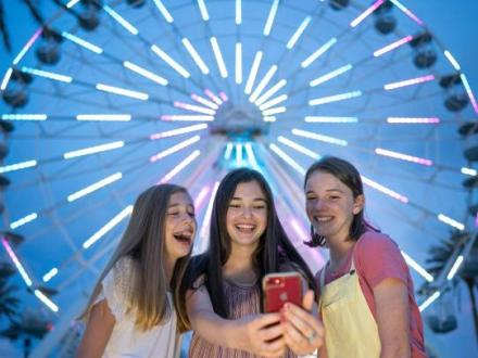 Girls taking a selfie in front of The Wharf Ferris Wheel on Alabama's Beaches