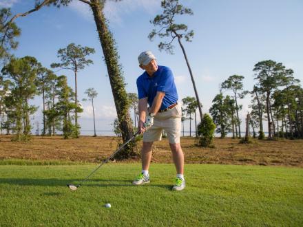 Man lining up a golf shot at Peninsula Golf & Racquet Club in Fort Morgan.