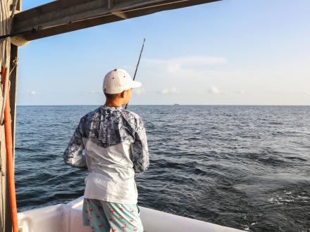 Angler fishing on a charter boat in Orange Beach at sunset