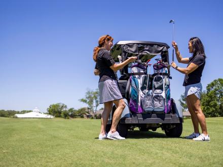 Women grabbing clubs from their golf cart at Craft Farms Golf Resort in Gulf Shores