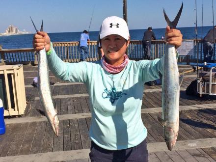 Woman holding two Spanish mackerel caught at the Gulf State Park Fishing Pier