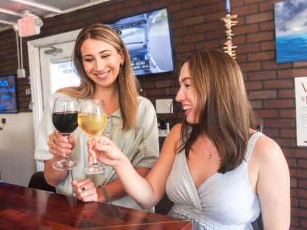 Women clinking wine glasses at Lauria's Wine Bar in Gulf Shores