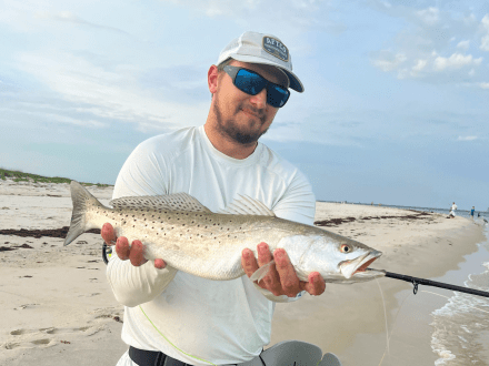 Man holding speckled trout caught surf fishing on Alabama's Beaches