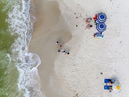 Drone shot of people walking and relaxing on the beaches of Gulf Shores