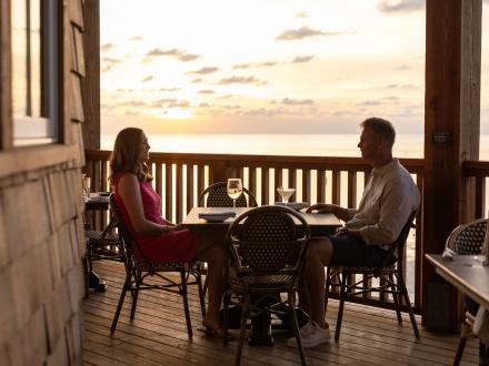 Couple dining outside at sunset at Jesse's on the Bay waterfront restaurant