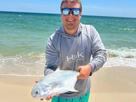 Man holding a pompano caught surf fishing in Orange Beach