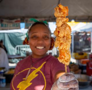 A Shimp Fest volunteer holds up fried food on a stick
